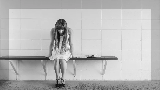 ベンチに座り俯く女性。整形後の後悔や内省をイメージさせる感情的なビジュアル。