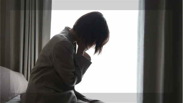 涙袋ヒアルロン酸に後悔してうつむく女性のシルエット